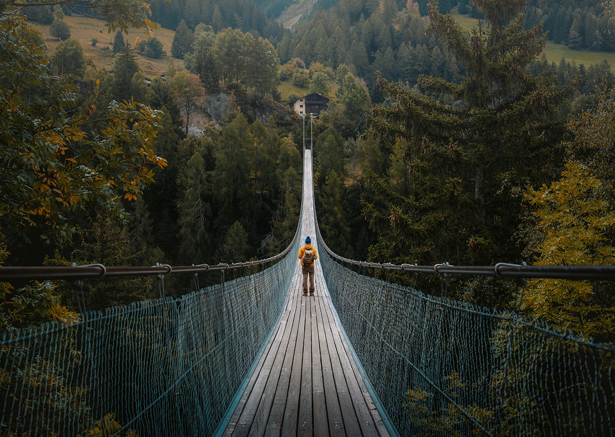 Young traveler man dressed in yellow jacket crosses hiking on an